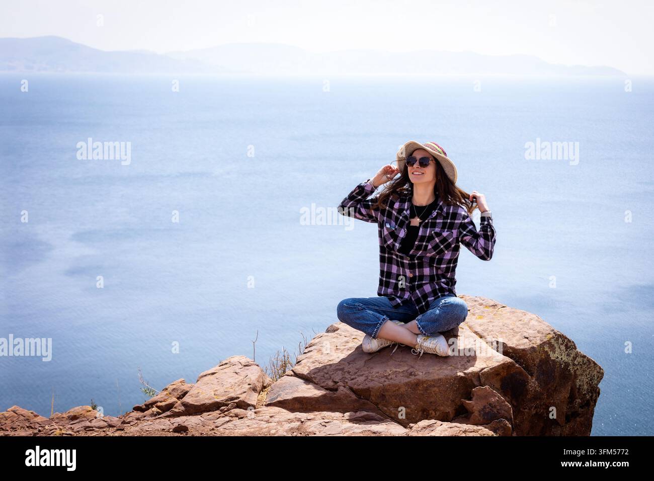 Touriste assise sur un rocher surplombant le lac Titicaca, Pérou Banque D'Images
