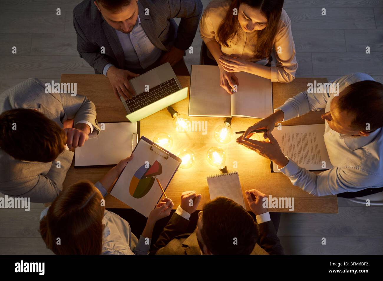 Vue aérienne d'une équipe d'affaires autour d'une table avec des ampoules, discutant des idées et planifiant une stratégie créative. Banque D'Images