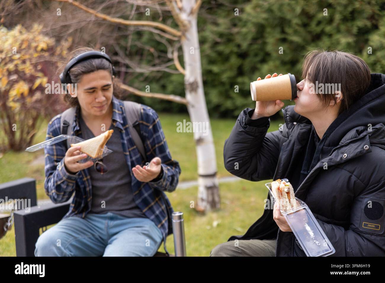 Étudiant buvant du café et mangeant un sandwich en plein air Banque D'Images
