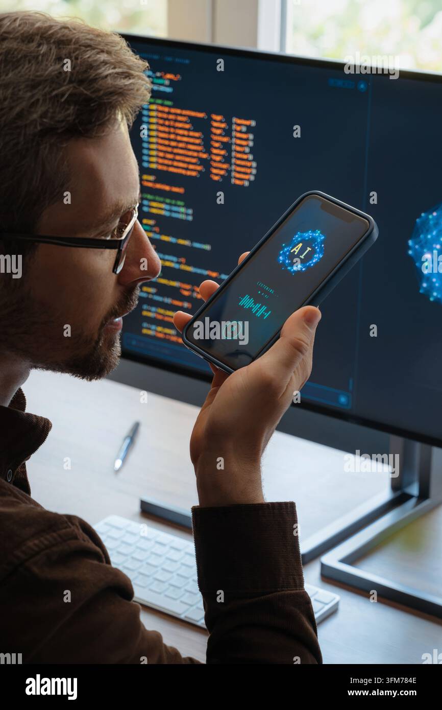 Vue par-dessus l'épaule d'un homme tenant un smartphone, discutant avec une application de chatbot IA, posant des questions, utilisant un assistant d'intelligence artificielle pour le travail et les tâches quotidiennes sur le téléphone et l'ordinateur. Banque D'Images