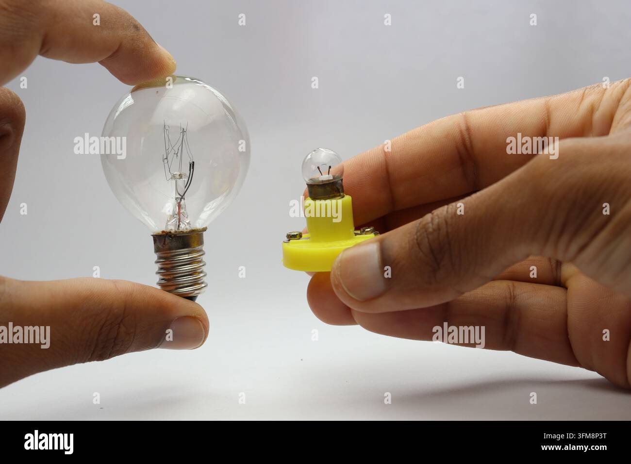 Main tenant deux types différents d'ampoules à incandescence pour comparaison Banque D'Images