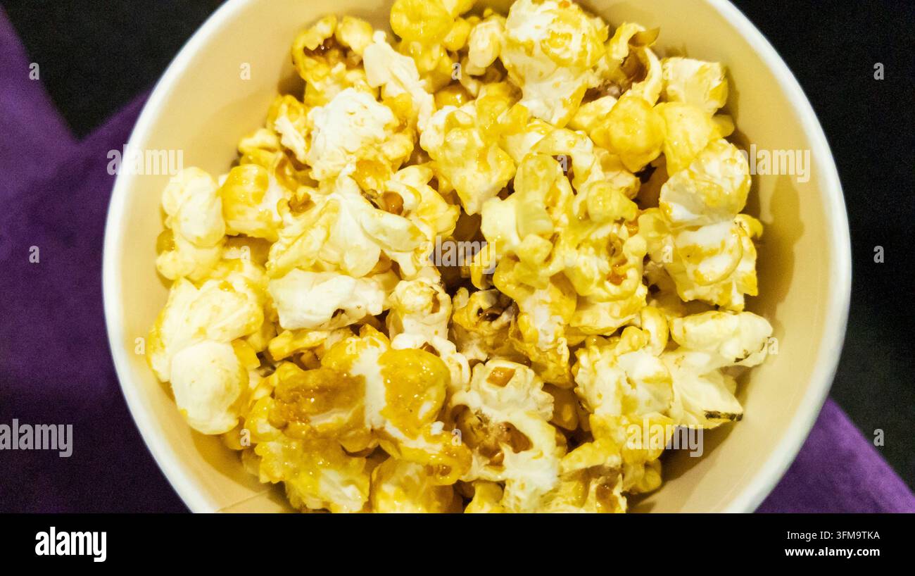 Seau de pop-corn frais, vue de dessus pour le divertissement en cinéma et concept de snack de cinéma. Snack de maïs beurré doré servi dans un récipient rond en papier Banque D'Images