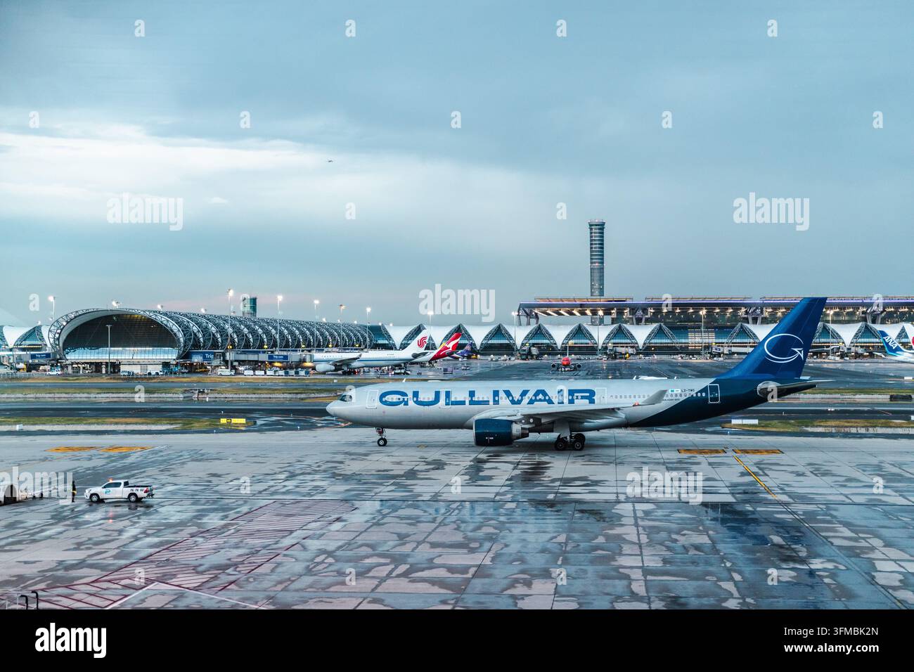 Bangkok, Thaïlande, 4 mai 2026 : Un Airbus A330 de GullivAir passe devant le complexe terminal emblématique de l'aéroport de Suvarnabhumi à Bangkok, Thaïlande. Banque D'Images