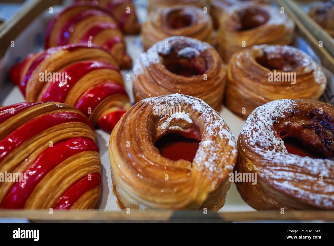 Des couches dorées et feuilletées et un glaçage rouge brillant : des croissants fraîchement cuits et des anneaux de pâtisserie feuilletés remplis de confiture, tout droit sortis du plateau de la boulangerie. Banque D'Images