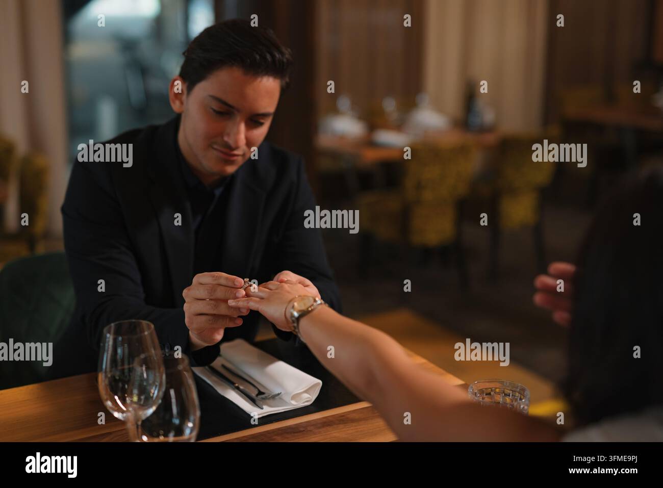 Moment romantique d'une demande en mariage, un jeune homme met une bague de fiançailles en diamant au doigt d'une femme, prise de vue en gros plan. Banque D'Images