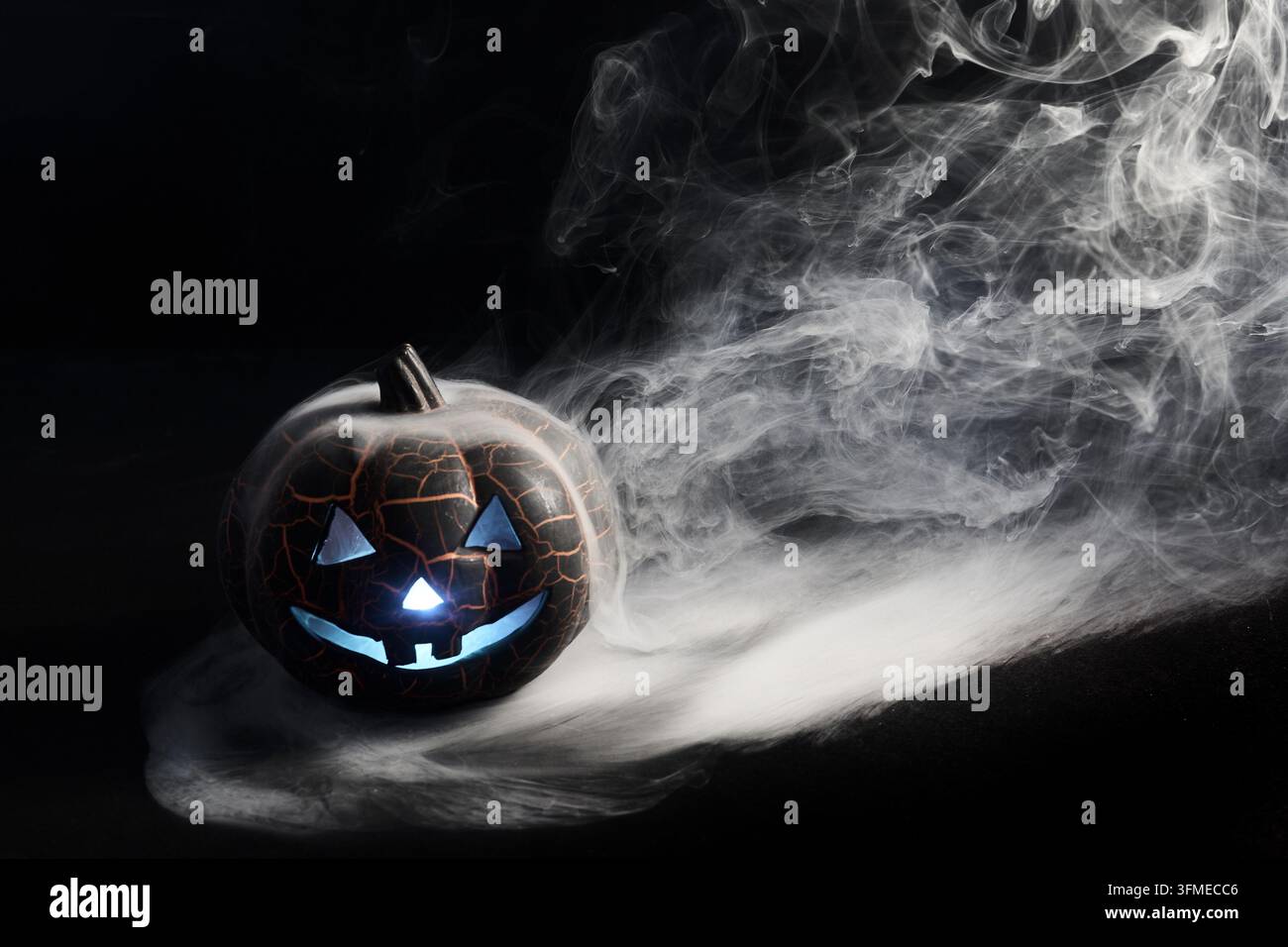 Citrouille d'Halloween brillant avec une lumière bleue et de la fumée Banque D'Images
