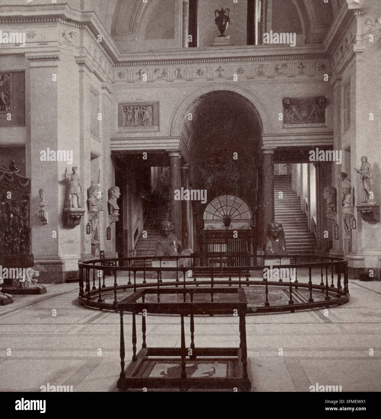 Photo vintage de la Munificence de Pie VI, Souverain Pontife. Cette photographie d’archive met en valeur la magnifique Sala a Croce Greca (Salle en croix grecque) à l’intérieur du Musée Pio-Clementino au Vatican, commandée sous le patronage du Pape Pie VI. Conçue à la fin du XVIIIe siècle par l’architecte Michelangelo Simonetti, la grande salle présente des statues classiques, des bas-reliefs et un portail majestueux flanqué de sphinxes en granit. Au centre, une barrière protectrice entoure la célèbre mosaïque de sol romaine antique représentant Athéna. L’image reflète magnifiquement la splendeur néoclassique et la profonde ant… Banque D'Images
