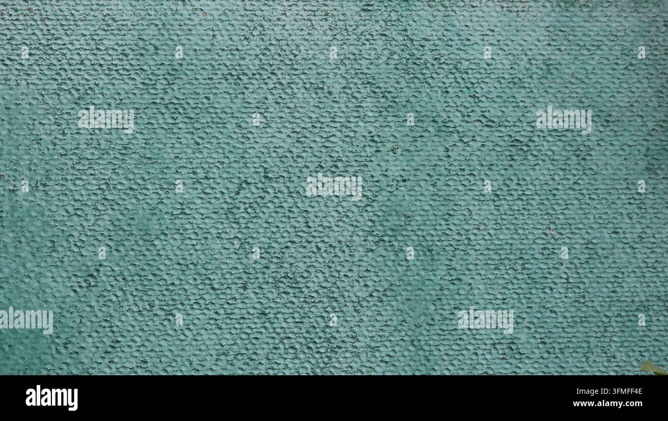 Texture d'un mur vert texturé avec du plâtre décoratif. Un fond rugueux présentant une finition à grains fins, des gouttelettes et une coloration irrégulière. Banque D'Images