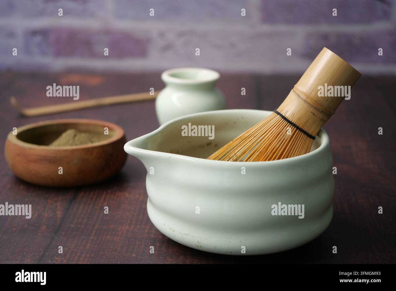Préparation du thé matcha avec fouet et bol sur une table en bois Banque D'Images