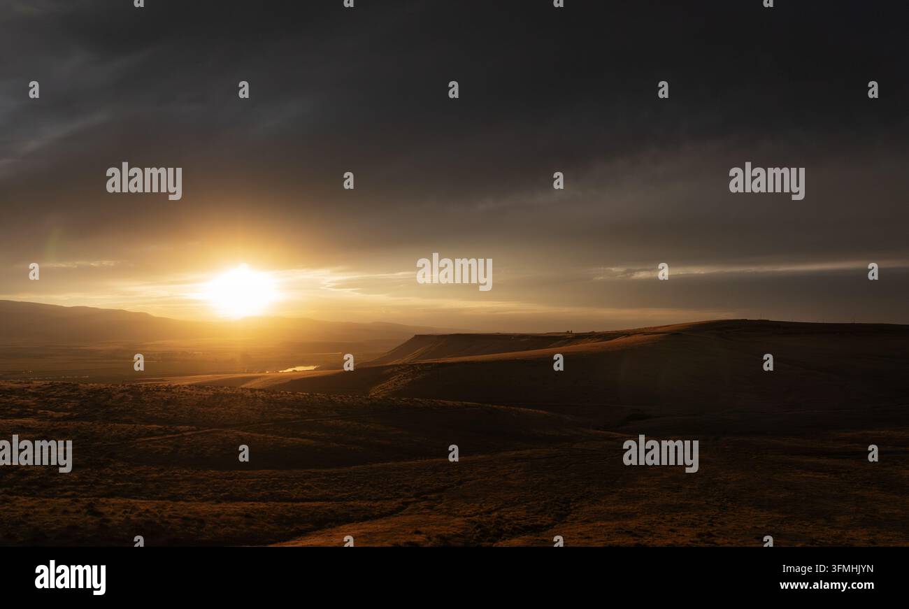 Scène dramatique de coucher de soleil sur un terrain vallonné avec des nuages Banque D'Images