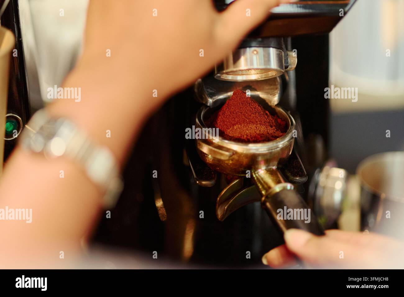 Femme broyant du café frais dans un portafiltre dans un café Banque D'Images