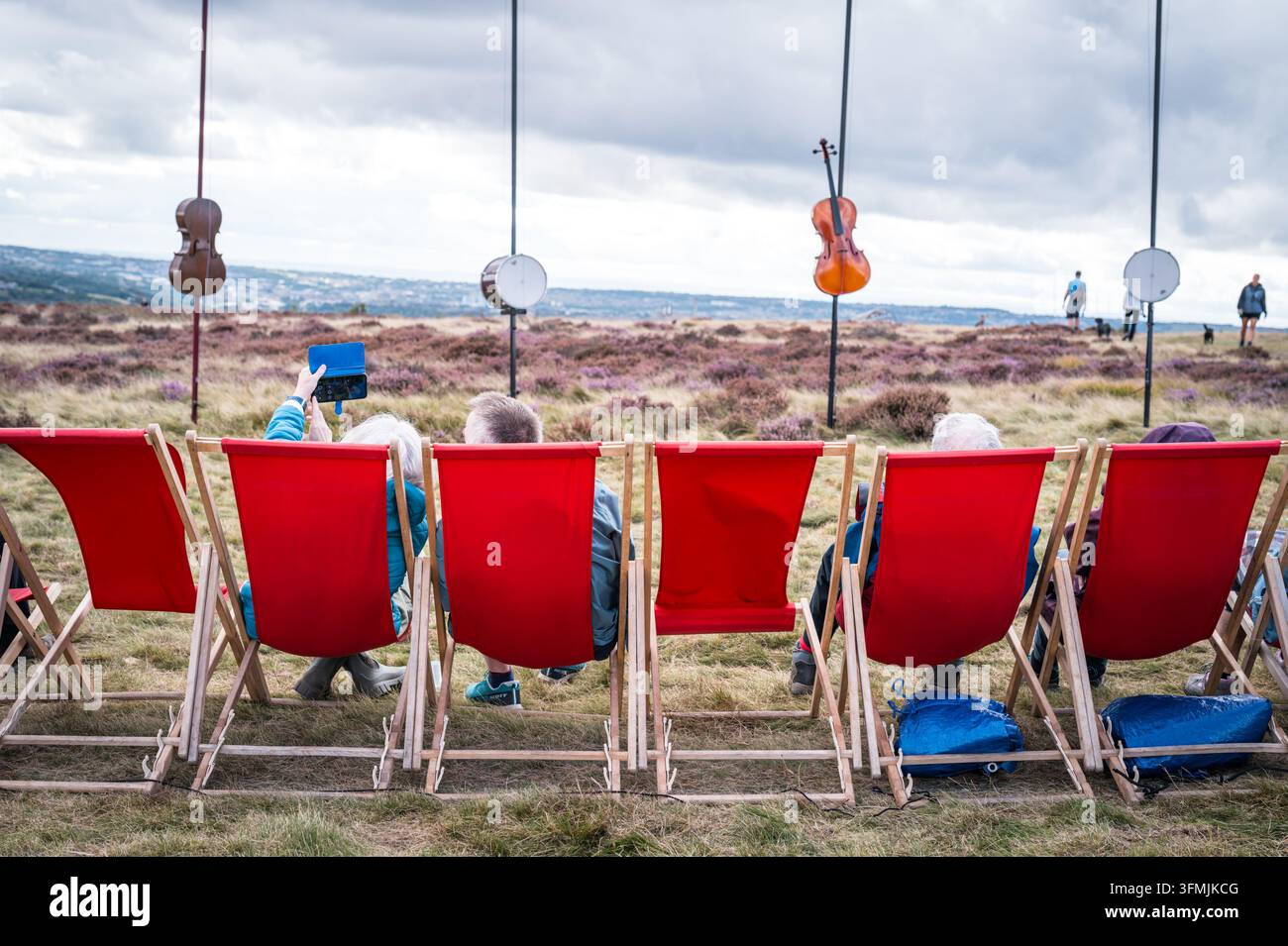 Baildon Moor, West Yorkshire : Les gens s'assoient pour profiter des sons de l'exposition d'art Harmonic Fields sur Baildon Moor. Banque D'Images