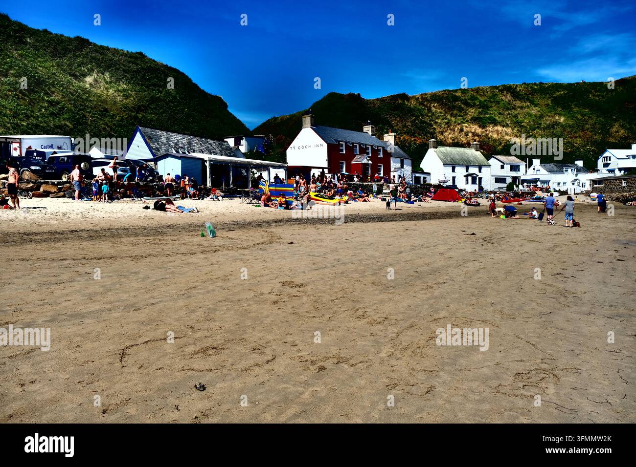 Touristes et baigneurs se détendent sur les rivages sablonneux de la plage de Porthdinllaen devant l'emblématique Ty Coch Inn sur la péninsule de Llŷn, dans le nord du Pays de Galles. Banque D'Images