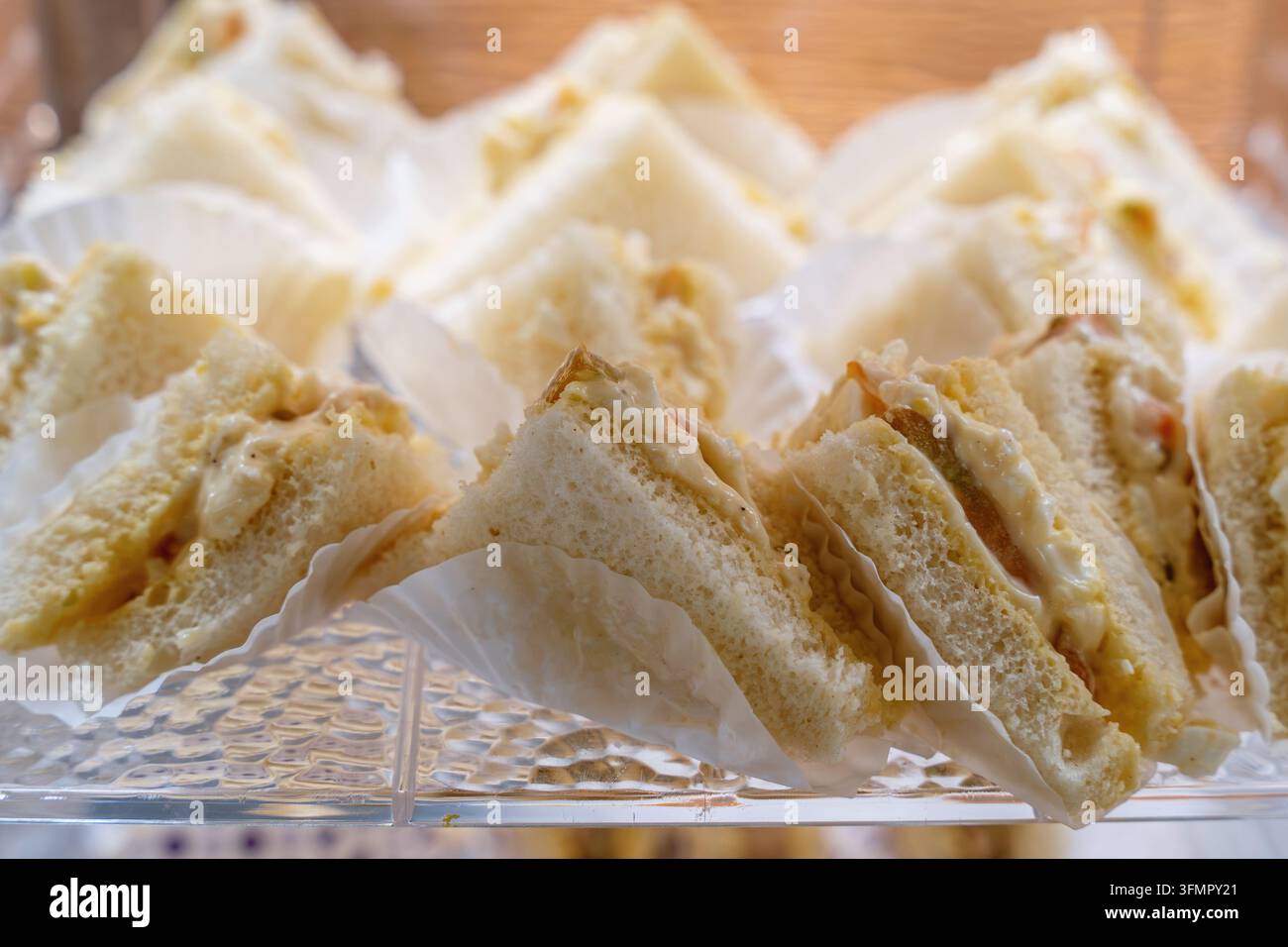 Assortiment de sandwiches au thé triangulaires frais servis sur un plateau en verre. Banque D'Images