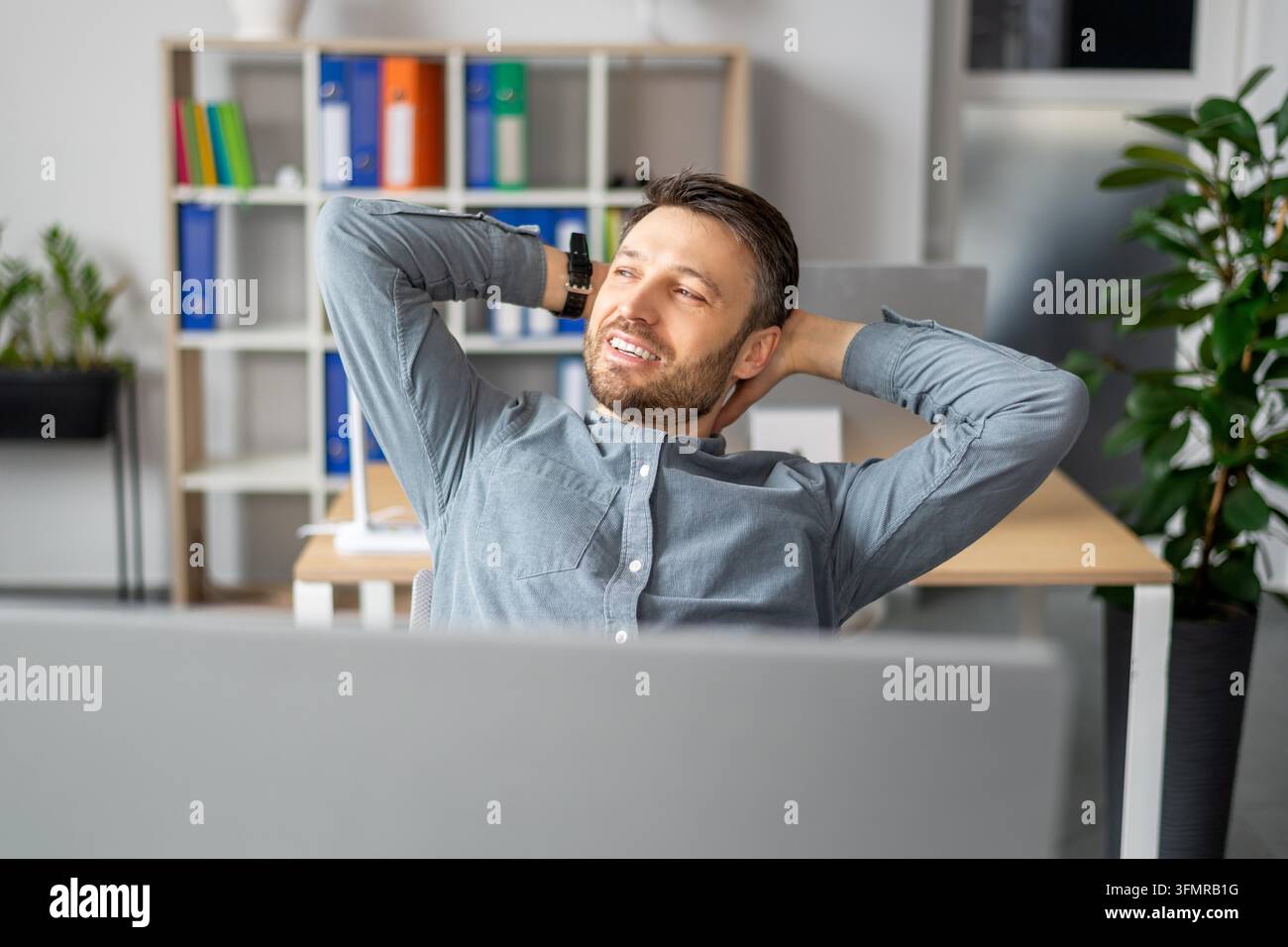 Homme caucasien souriant se détendant au bureau, profitant d'une pause travail, concept d'affaires Banque D'Images