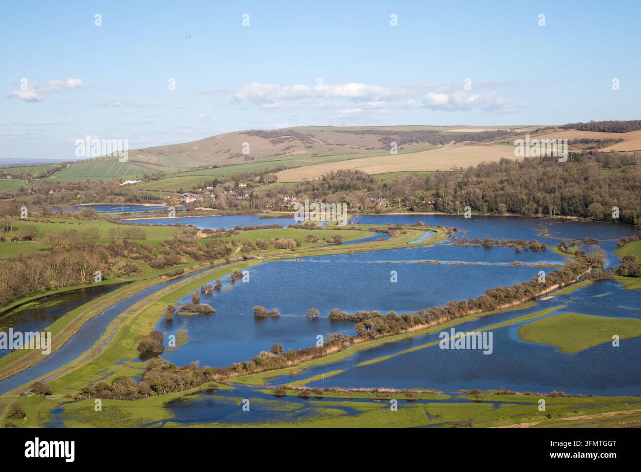 Vue en hauteur des méandres de la rivière Cuckmere et des prairies de vallée inondées sous un ciel bleu clair, Parc national des South Downs, East Sussex, Angleterre, Royaume-Uni. Banque D'Images