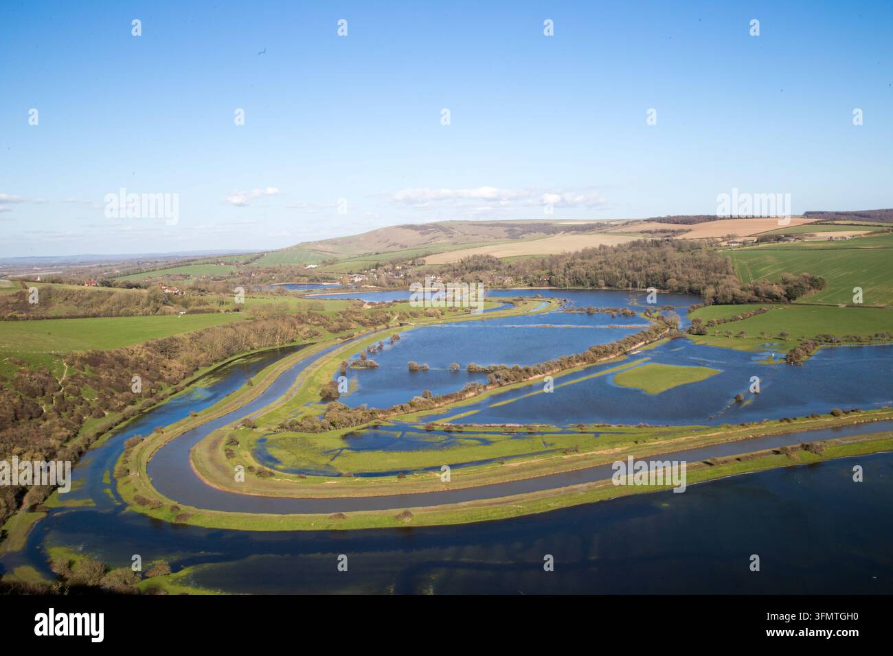Vue en hauteur des méandres de la rivière Cuckmere et des prairies de vallée inondées sous un ciel bleu clair, Parc national des South Downs, East Sussex, Angleterre, Royaume-Uni. Banque D'Images