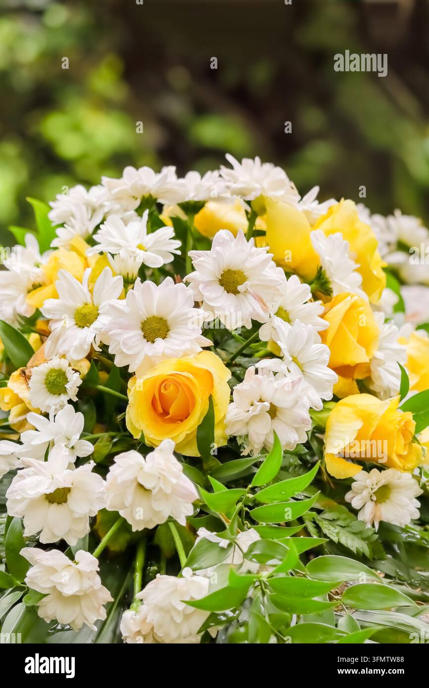 Le lieu de repos final. Arrangement floral sur une tombe d'urne. Roses jaunes et fleurs blanches et vertes au cimetière. Un beau bouquet. Banque D'Images