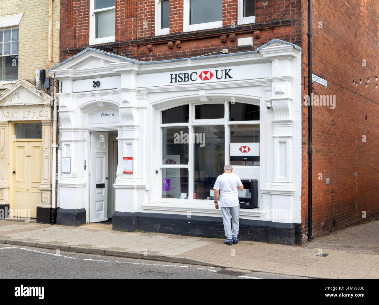 Personne utilisant un distributeur de billets d'HSBC dans une petite succursale à Saxmundham, Suffolk, Angleterre, Royaume-Uni Banque D'Images