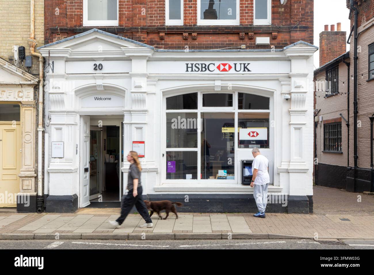 Personne utilisant un distributeur de billets d'HSBC dans une petite succursale à Saxmundham, Suffolk, Angleterre, Royaume-Uni Banque D'Images