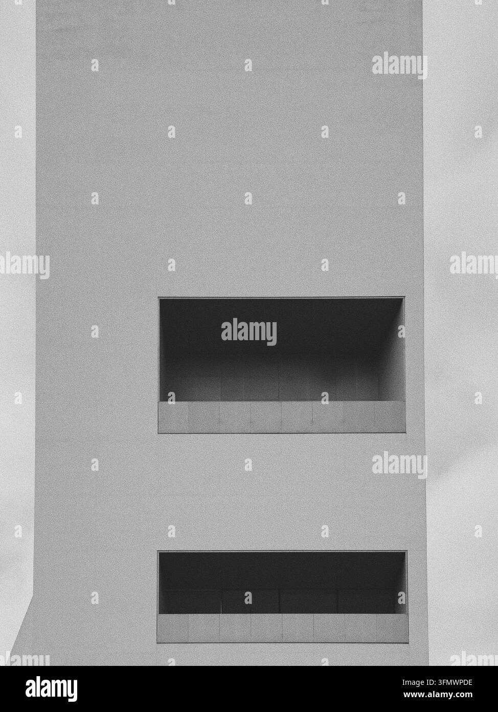 Un détail architectural noir et blanc serré et granuleux des ouvertures rectangulaires des fenêtres sur la façade en béton sobre du Torre. Banque D'Images