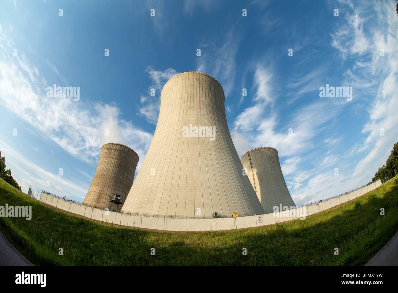 Vue des grandes tours de refroidissement en béton d'une centrale nucléaire sous un ciel bleu éclatant parsemé de nuages fins en Tchéquie. Banque D'Images