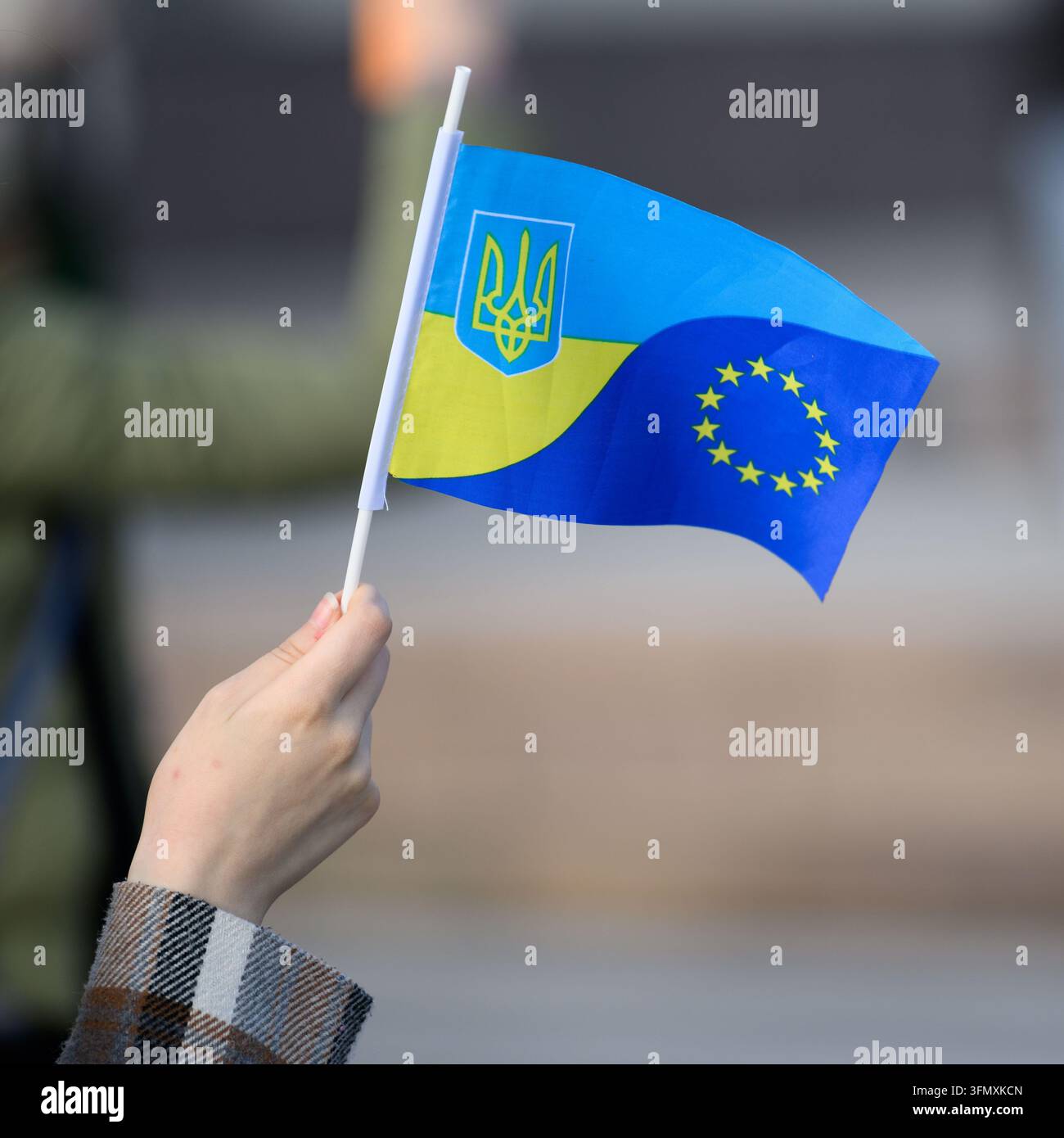 Main tenant un petit drapeau national combinant les symboles de l'Ukraine et de l'Union européenne Banque D'Images