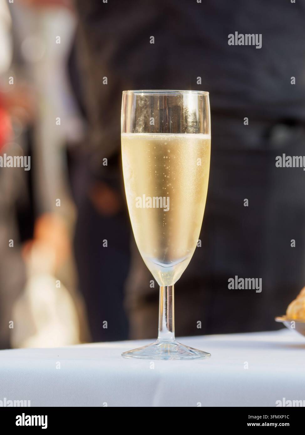 Verre de vin blanc pétillant sur une table avec un fond flou. Banque D'Images