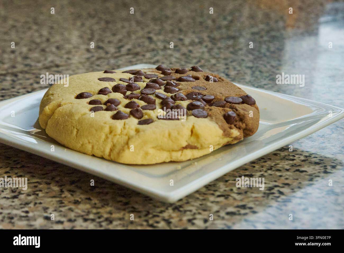 Cookie combinant de la pâte à la vanille et au chocolat avec des pépites de chocolat sur un plan de travail en granit Banque D'Images