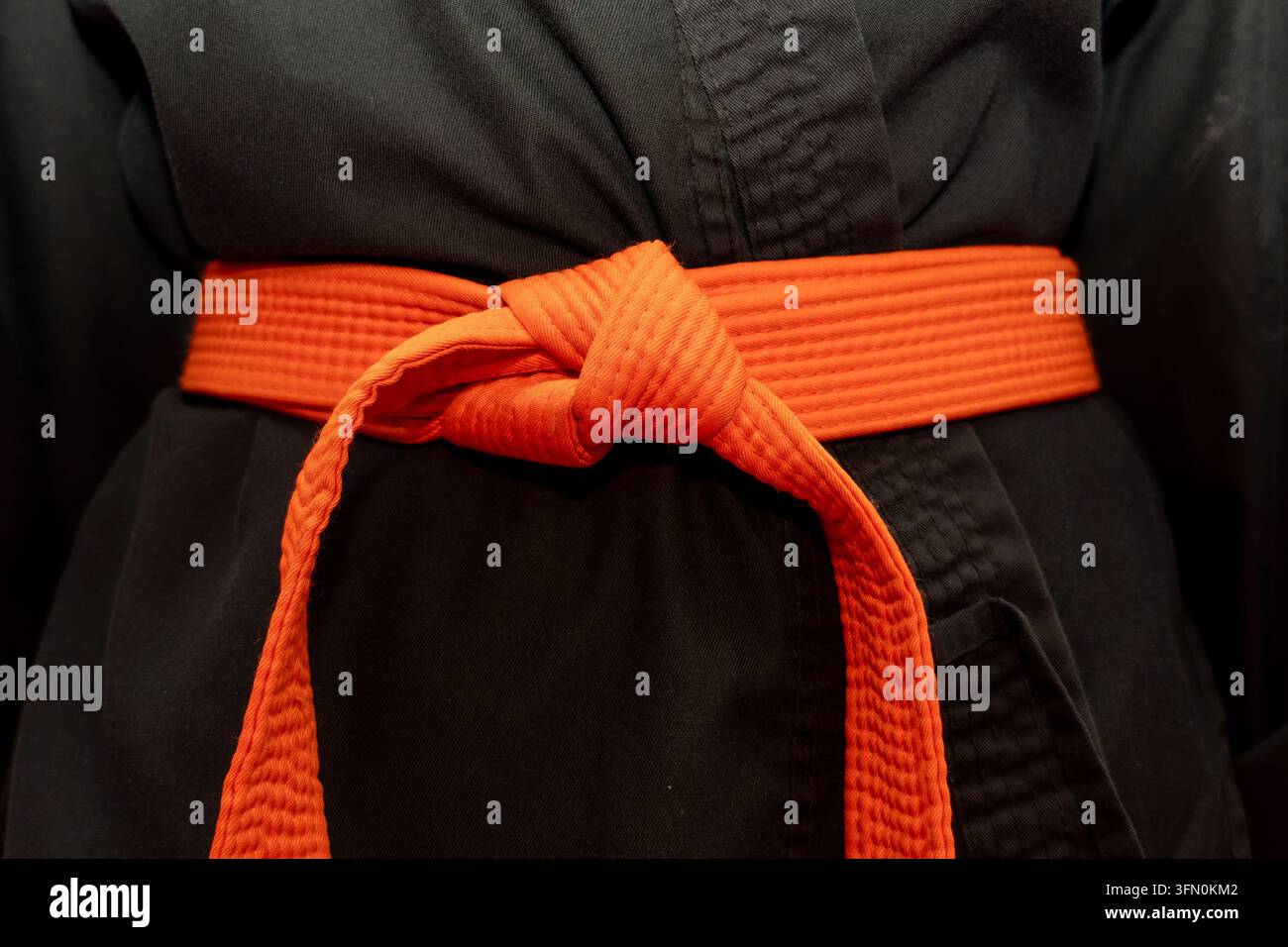 Élève de hapkido portant une ceinture orange et un uniforme noir Banque D'Images