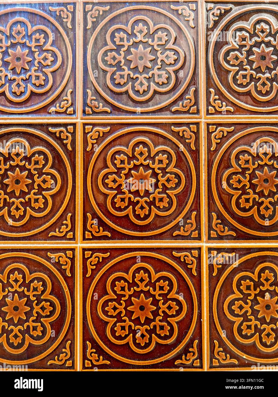 Carreaux de céramique azulejo glacés brun avec médaillons floraux en relief formant un motif mural répétitif au Portugal - Image de stock capturée avec un smartphone