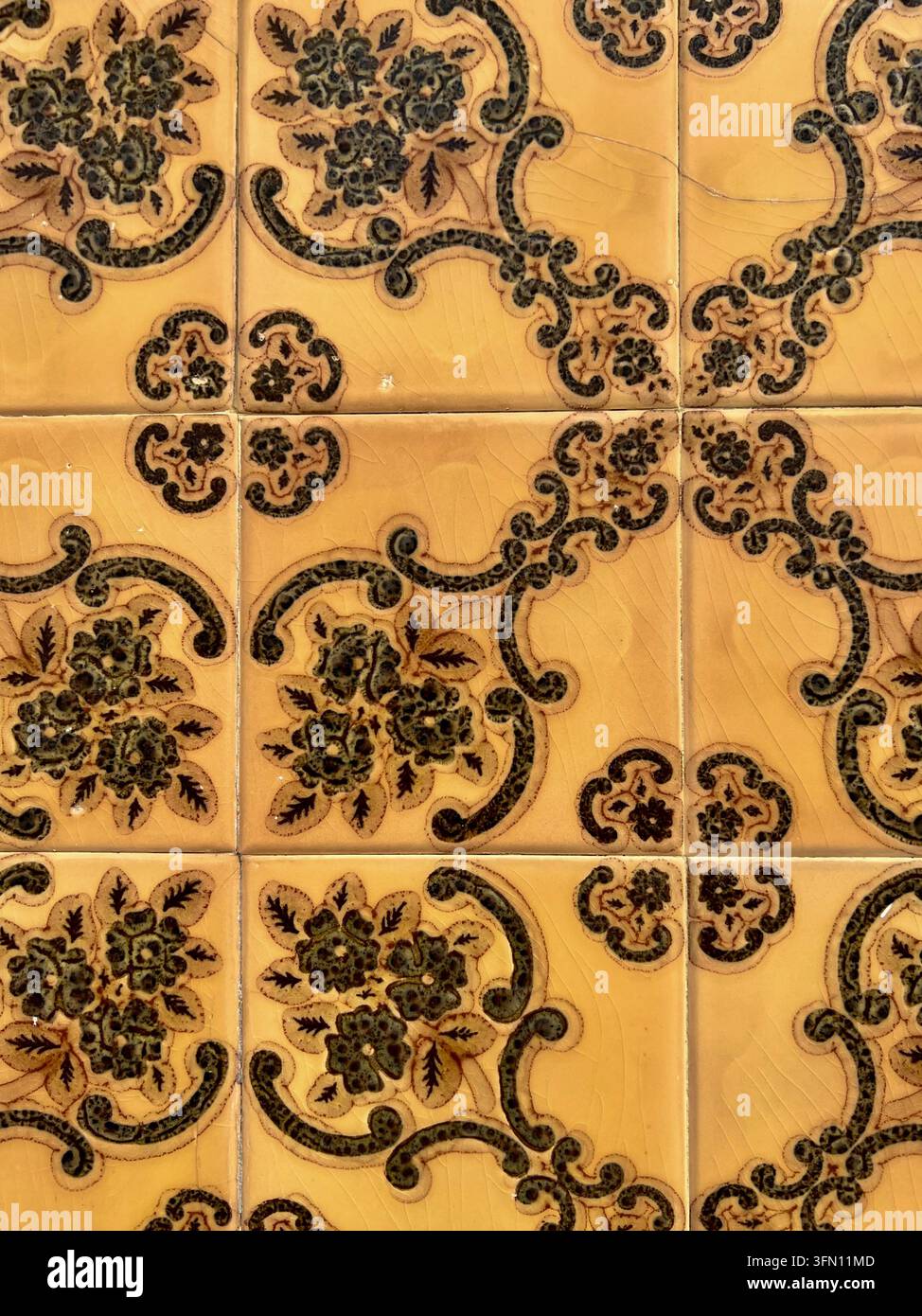 Carreaux de wall azulejo portugais ocre avec un motif floral et enroulé vert foncé en relief au Portugal - Image de stock capturée avec un smartphone