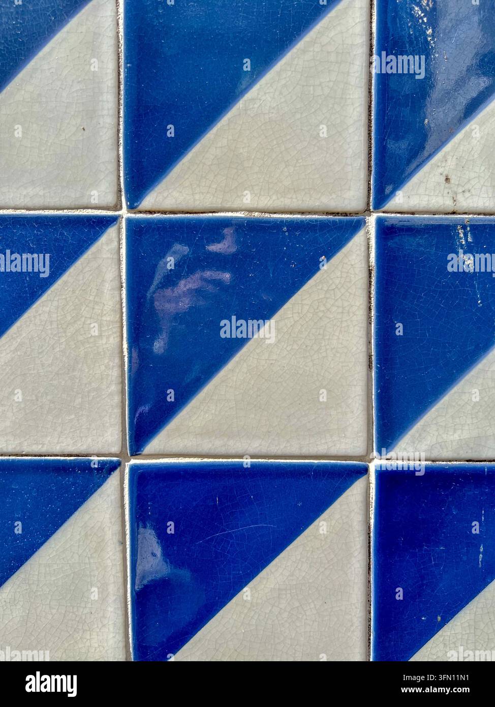 Carreaux azulejo bleus et blancs avec un motif triangulaire diagonal et une glaze craquelée sur un mur au Portugal - Image de stock capturée avec un smartphone