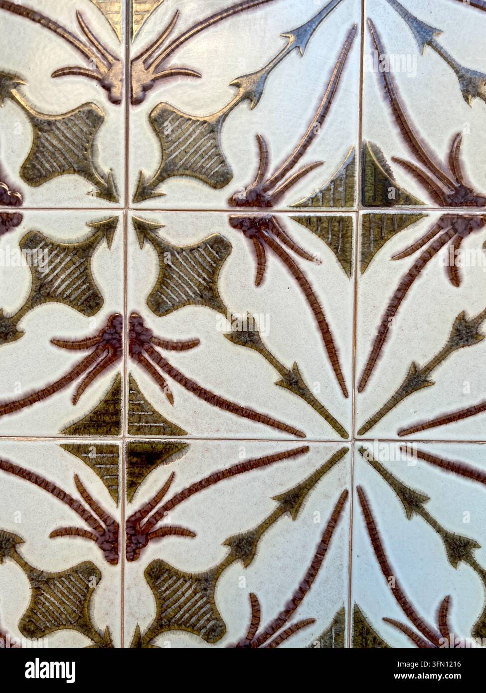 Carreaux de céramique azulejo glacés au Portugal avec un motif botanique répété vert olive et brun sur fond crème. - Image de stock capturée avec un smartphone