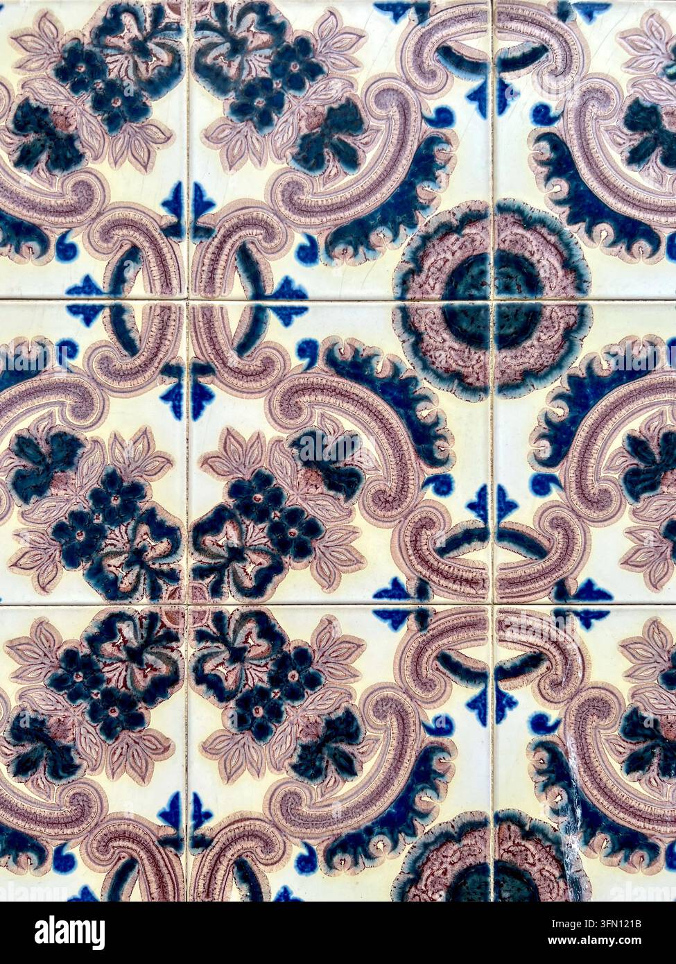 Carreaux azulejo portugais au Portugal avec des volutes violettes et des fleurs bleues se répétant sur un mur émaillé crème. - Image de stock capturée avec un smartphone
