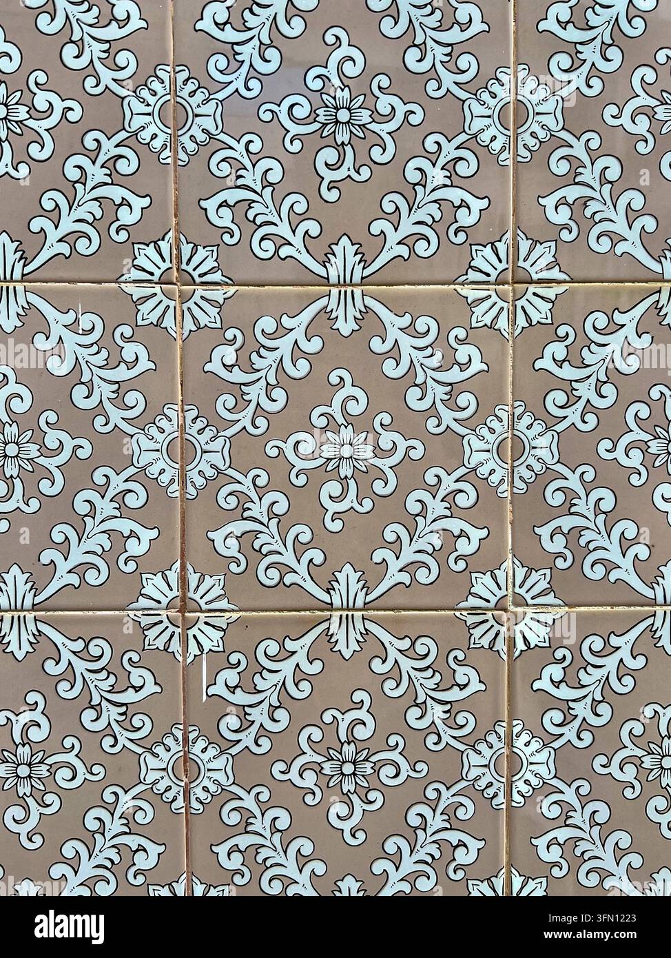 Carreaux de faïence portugais (azulejo) au Portugal avec des volutes florales blanches et des rosettes sur un fond émaillé beige Banque D'Images
