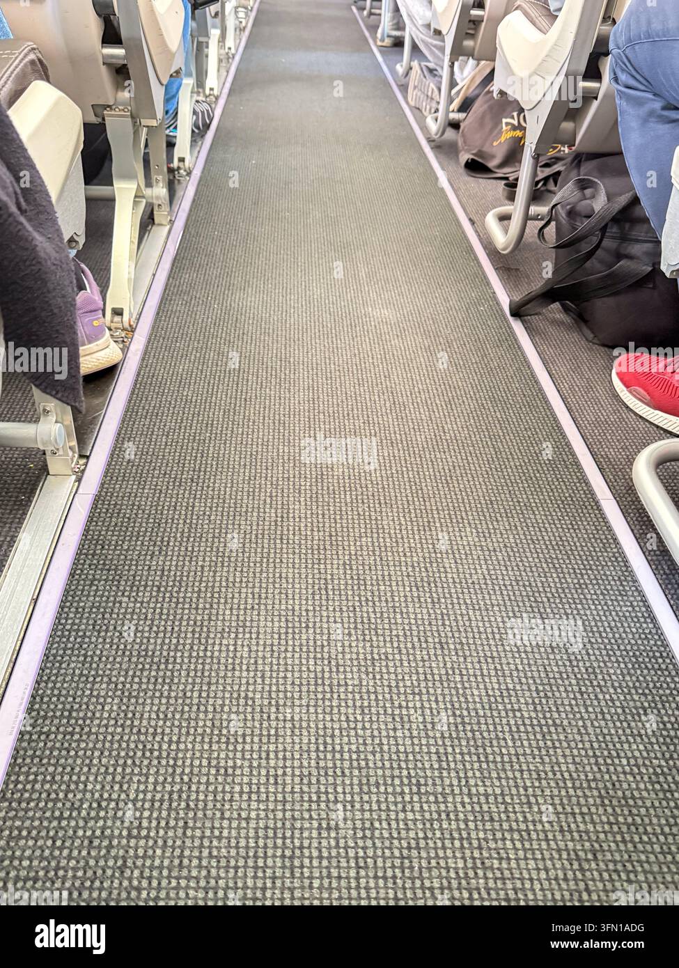 Allée de cabine d'avion avec sièges de passagers et pieds – Vue intérieure d'un vol commercial Banque D'Images