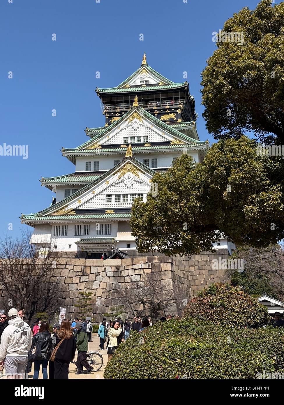Touristes visitant la tour principale du château d'Osaka par une journée ensoleillée Banque D'Images
