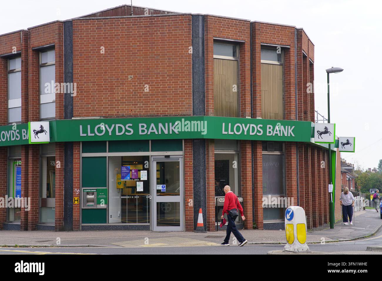 Homme traversant devant le coin de la Lloyds Bank à Haywards Heath, en Angleterre. Banque D'Images