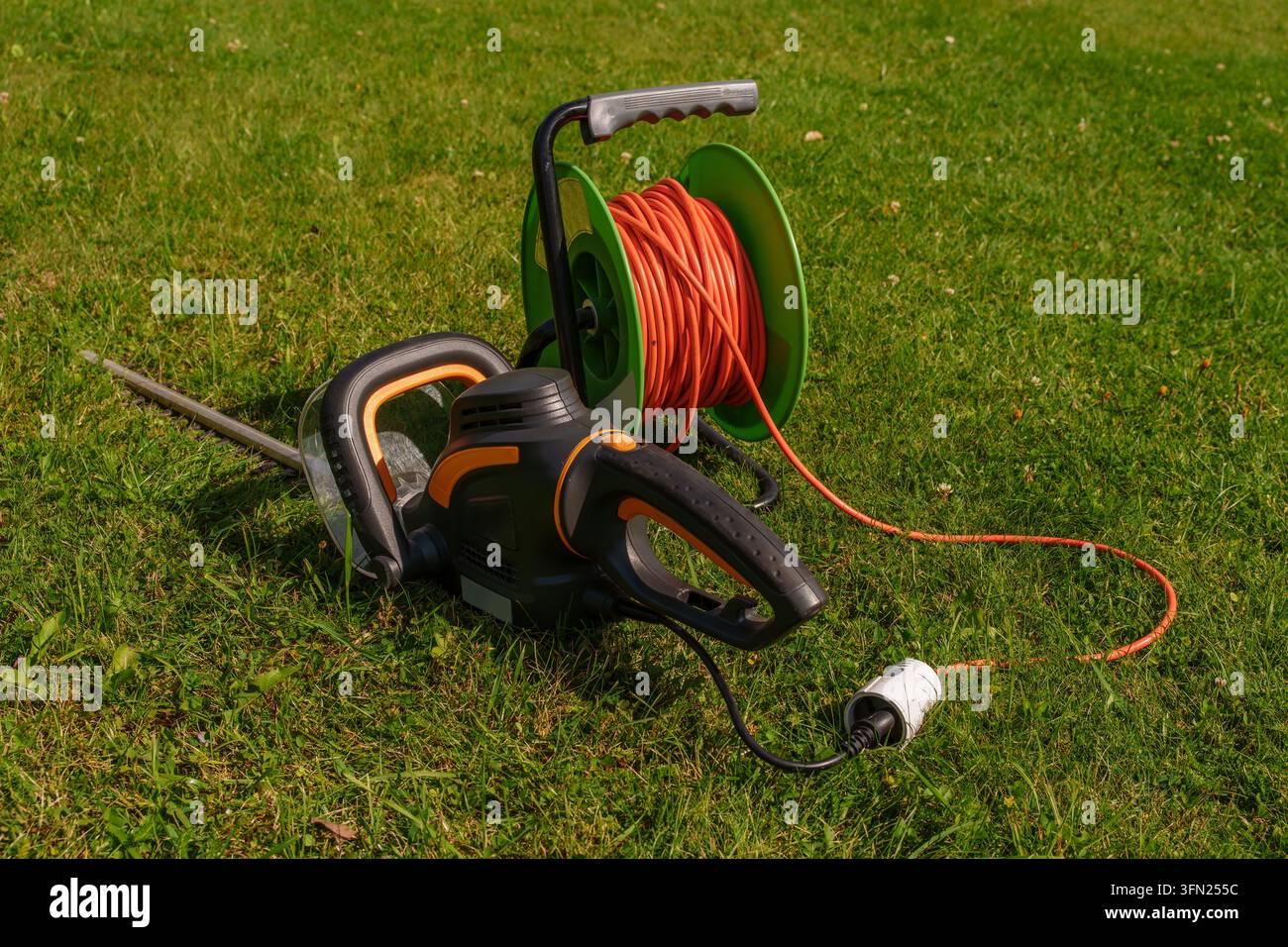 Tondeuse à haies électrique avec bobine de câble d'extension sur l'herbe verte Banque D'Images