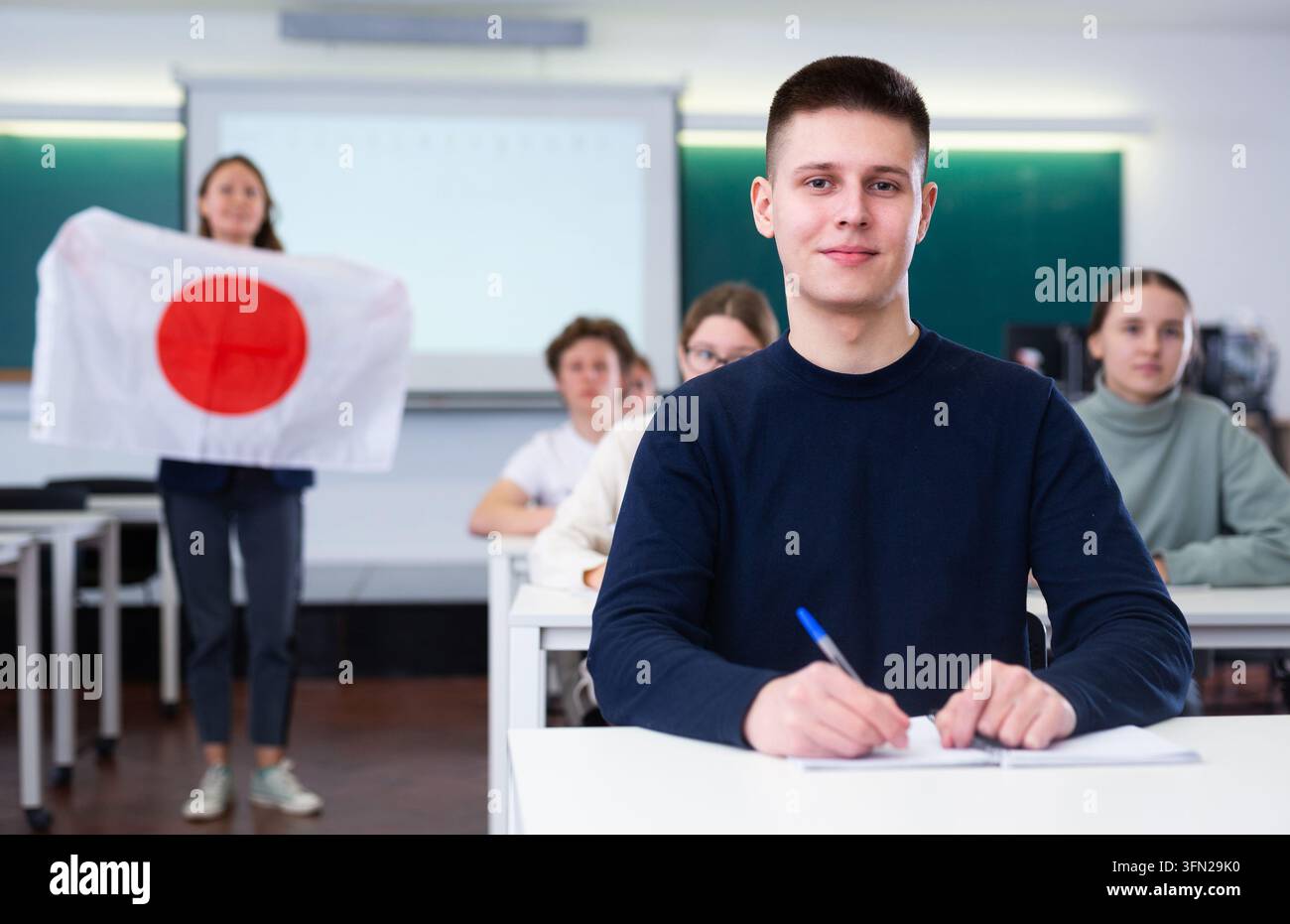 Un professeur de lycée parle aux élèves du Japon et tient un drapeau japonais en main. Banque D'Images