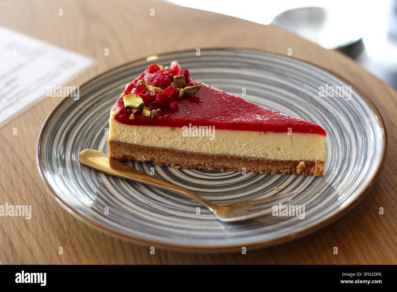 Tranche de cheesecake aux framboises cuit au four avec pistaches dans l'assiette Banque D'Images
