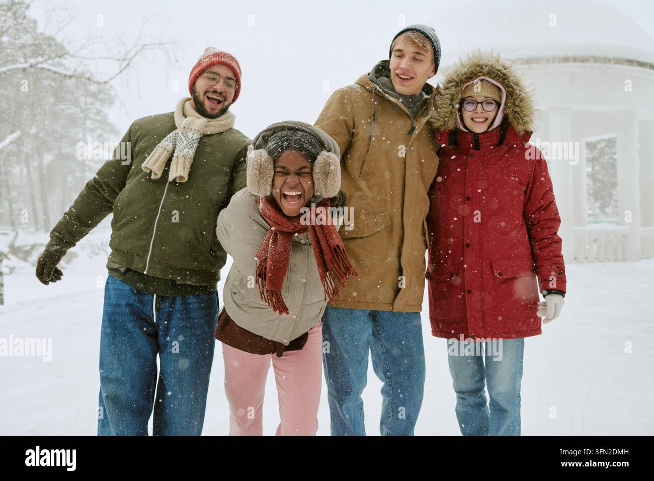 Des amis divers s'amusant et riant en plein air en hiver Banque D'Images