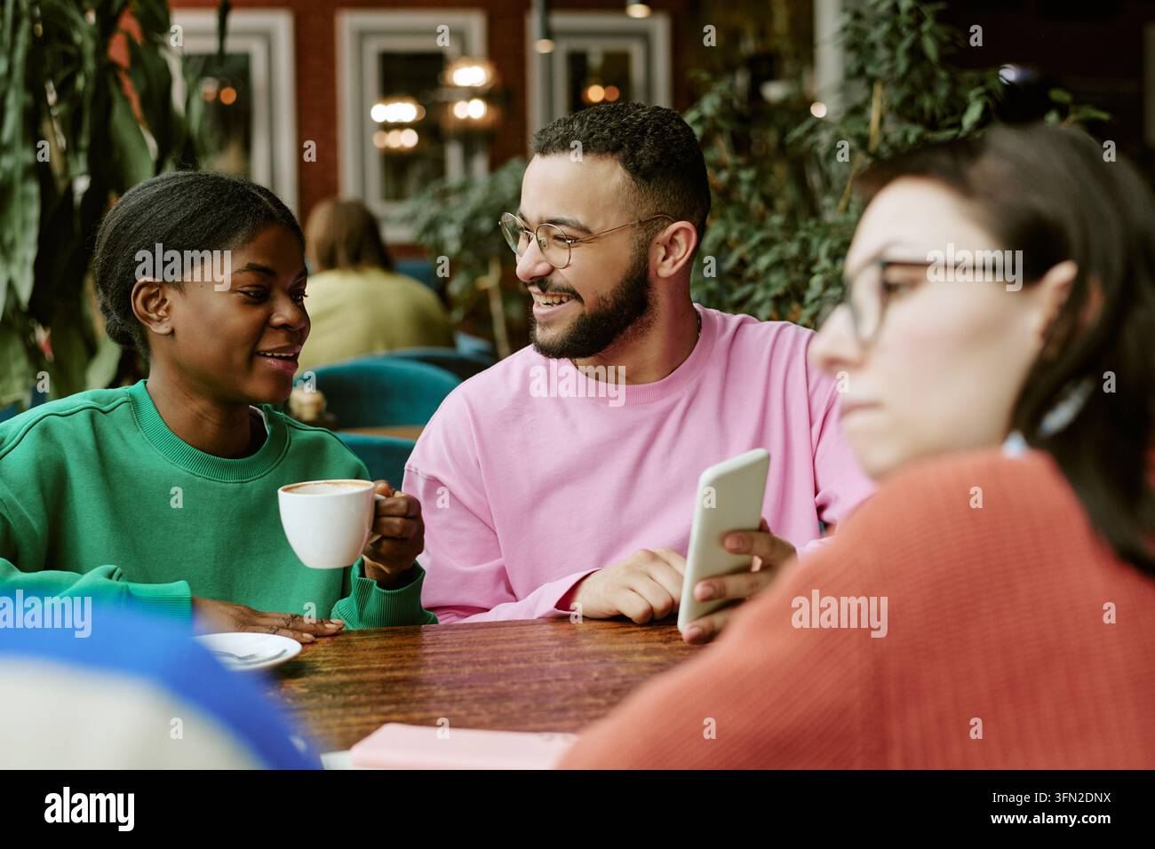 Groupe divers d'amis discutant et regardant un smartphone dans un café Banque D'Images