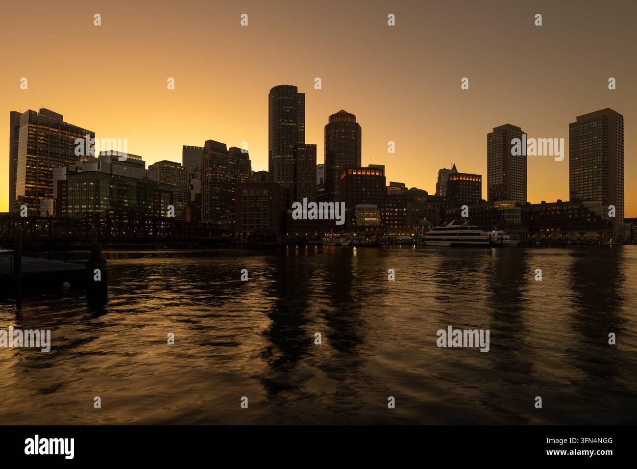 Coucher de soleil sur le centre-ville de Boston, États-Unis, vu à travers le port depuis le Seaport District, avec des yachts amarrés et des bâtiments riverains. Banque D'Images