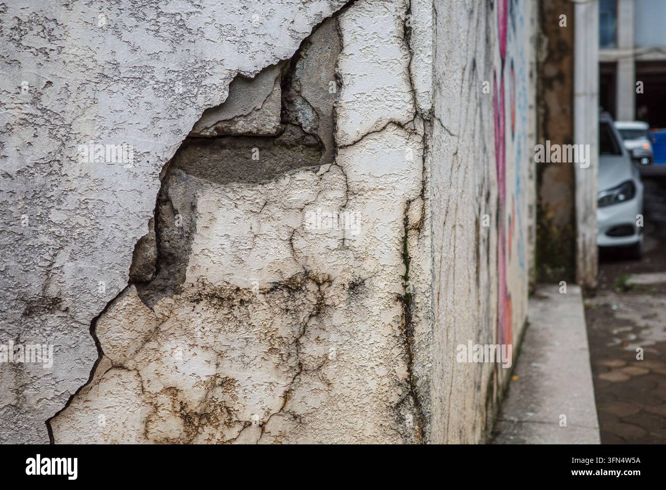 Mur fissuré avec enduit écaillant, dommages dus à l'humidité et à la moisissure sur la maçonnerie nécessitant réparation, rénovation et étanchéité après une détérioration prolongée et la négligence du bâtiment. Banque D'Images