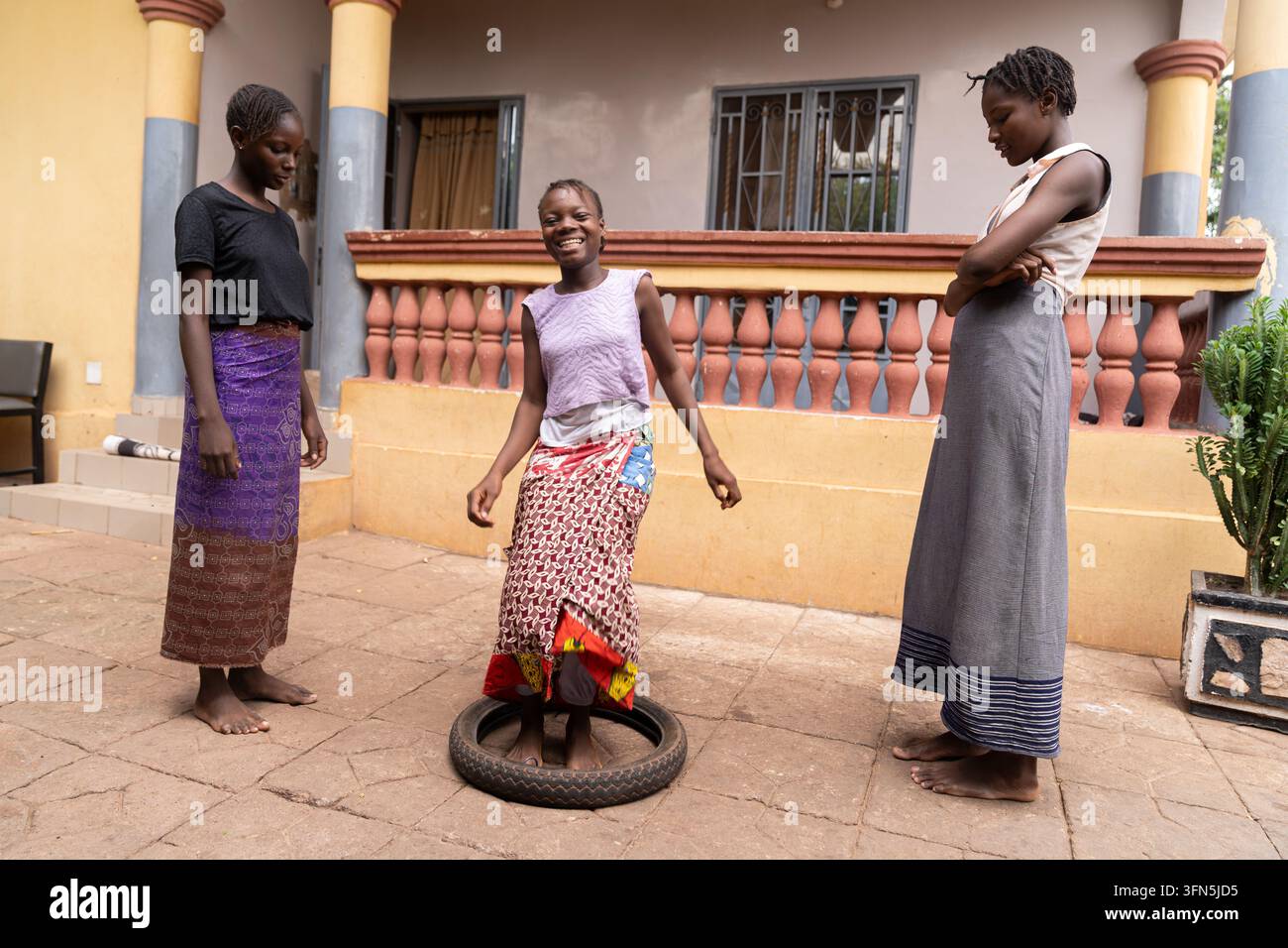 Couturière africaine souriante travaillant à une machine à coudre avec un tissu coloré, représentant un travail qualifié, l’entrepreneuriat, la mode durable et les femmes’ Banque D'Images