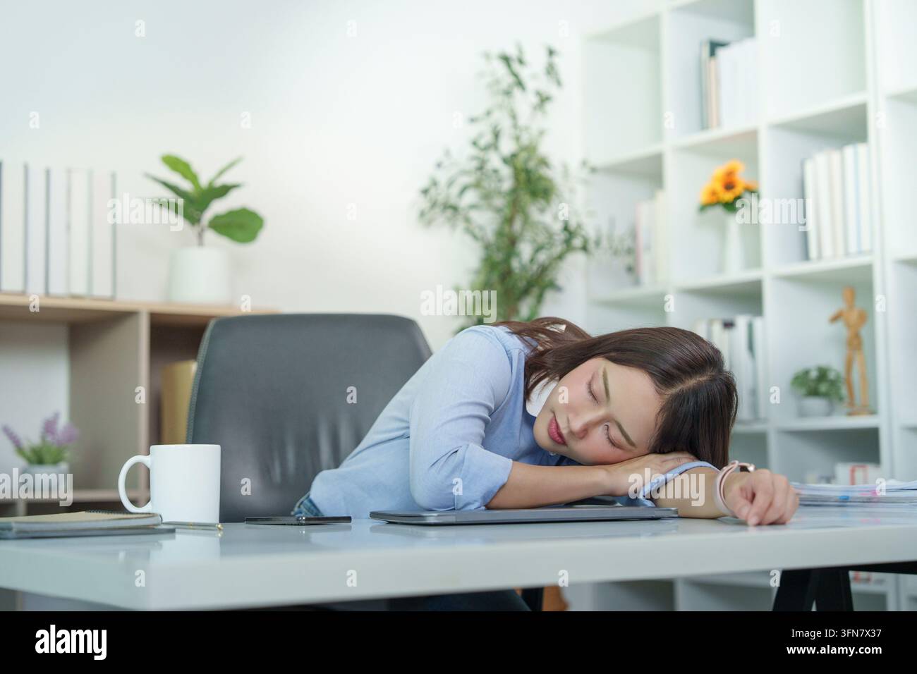 Femme d'affaires asiatique dormant à son bureau de bureau à cause de l'épuisement et du syndrome de bureau Banque D'Images