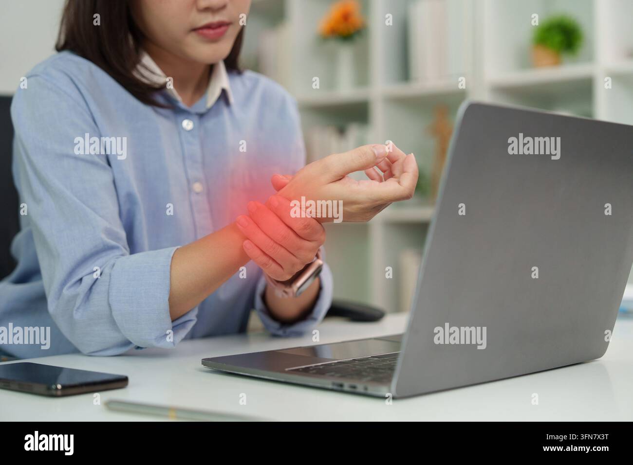 Employé de bureau asiatique souffrant de douleurs au poignet et du syndrome du bureau au bureau d'ordinateur portable Banque D'Images
