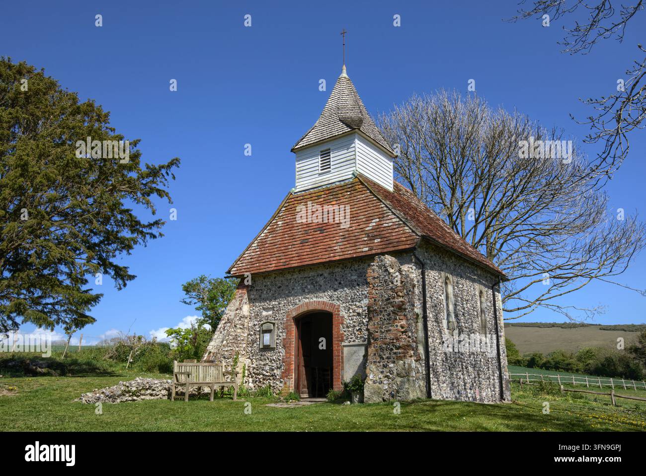 L'église historique de Lullington du XIIIe siècle, connue comme la plus petite église du Sussex, se dressant sous un ciel bleu clair dans les South Downs. Banque D'Images